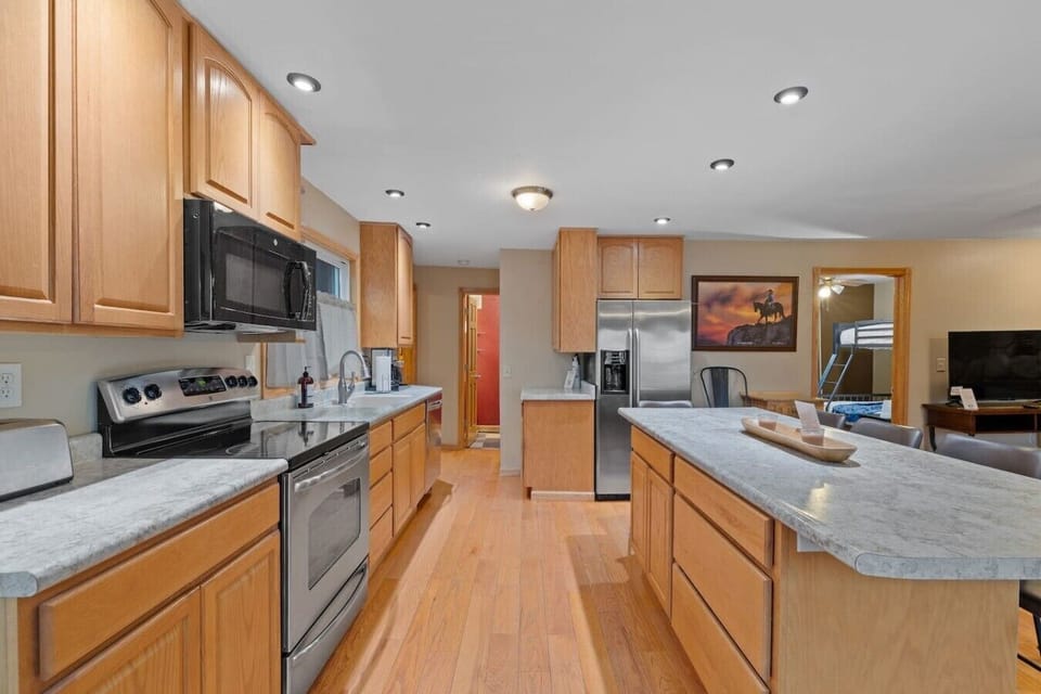 A spacious, fully equipped kitchen featuring generous counter space, stainless steel appliances, ample cabinetry, and a large island perfect for meal prep and gathering.