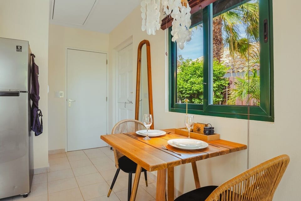 Dine beside a picture-perfect tropical view, where warm wood, woven chairs, and lush greenery make every meal feel special.