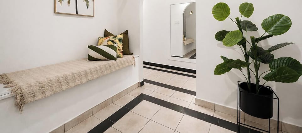 Bright tropical-inspired common area with arched entry and cozy bench seating