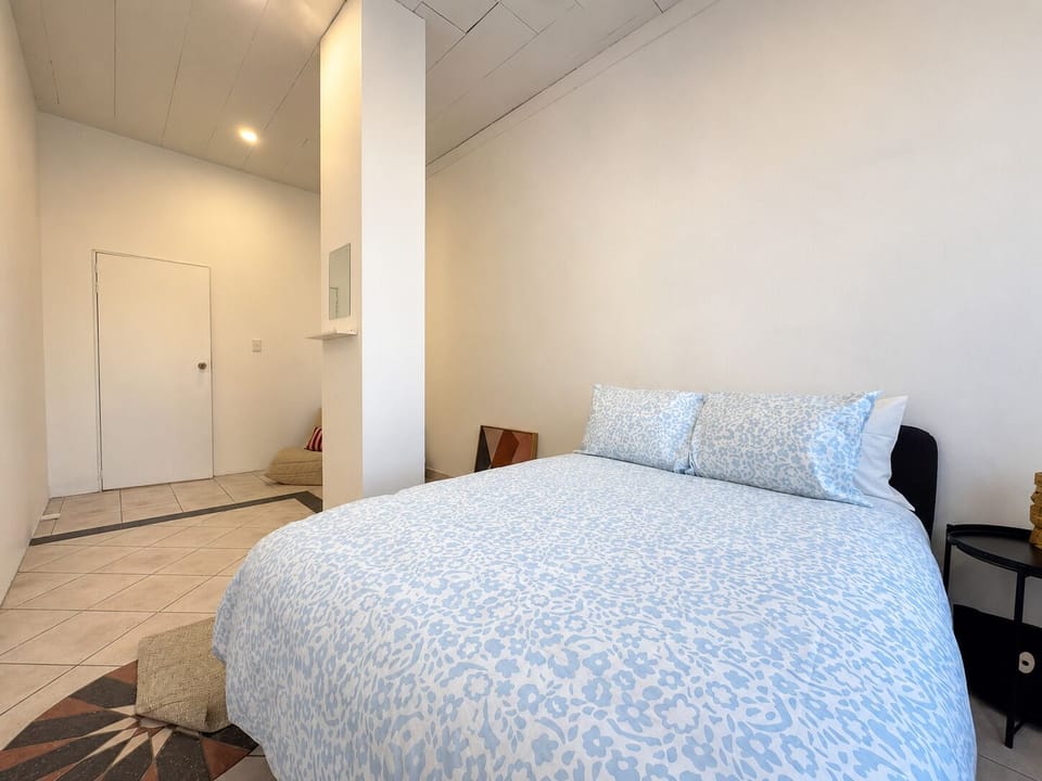 Bright minimalist bedroom with airy high ceilings and cozy double bed