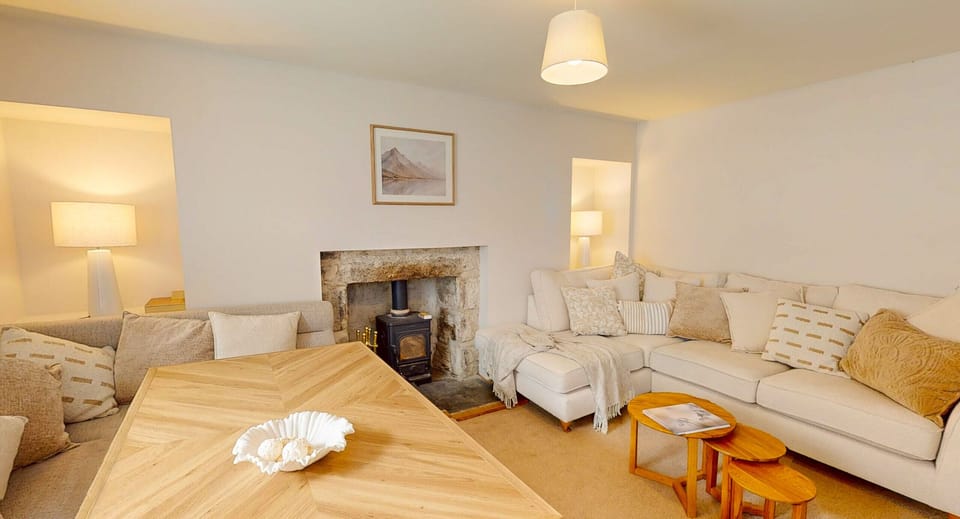 Sofas facing each other across the fireplace, with lamps lit at either end. The floor is bare wood and the walls kept pale.