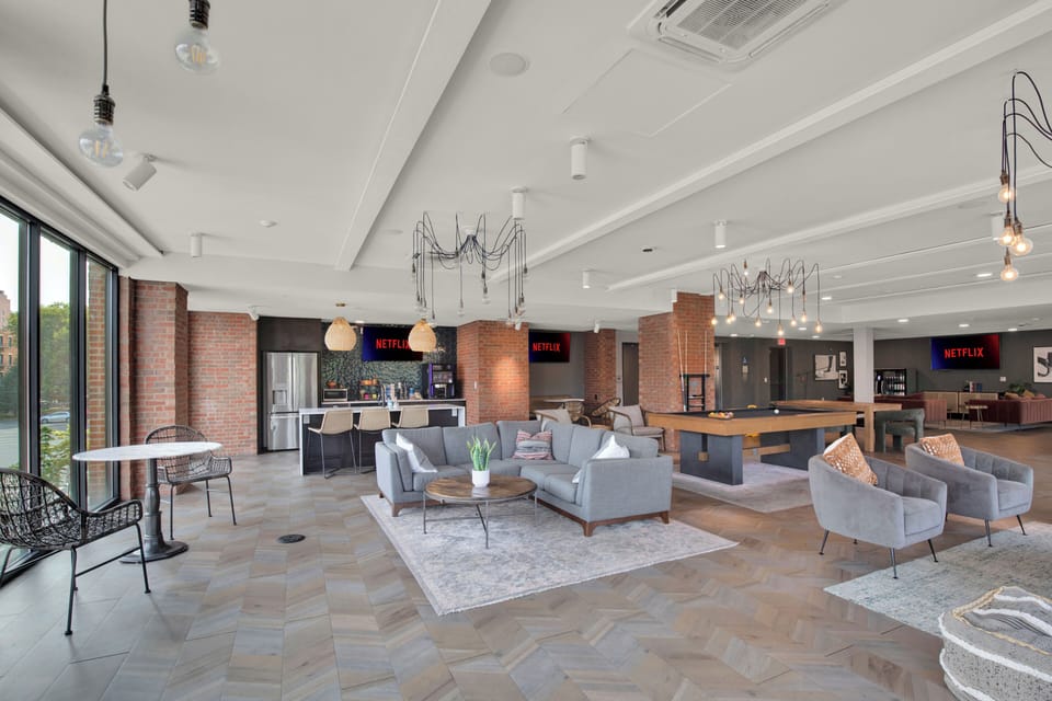 Spacious modern lounge with game table, kitchenette, and natural light