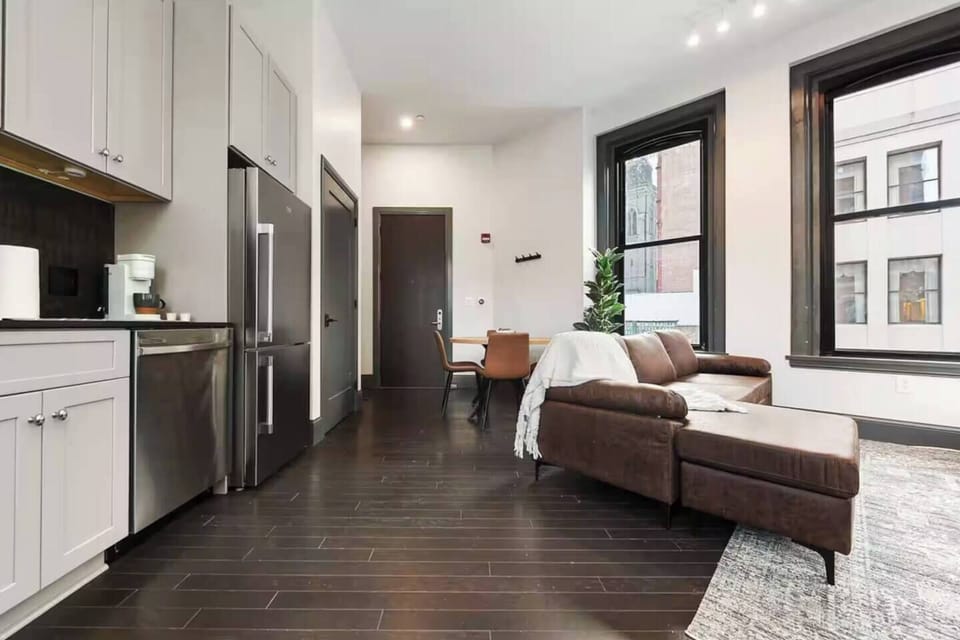 Bright modern studio with large windows, sleek kitchen, and cozy lounge area