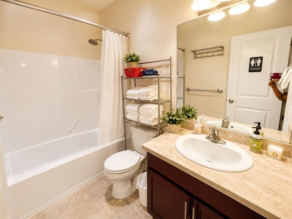 Bright full bathroom with tub-shower, large vanity, and fresh towels