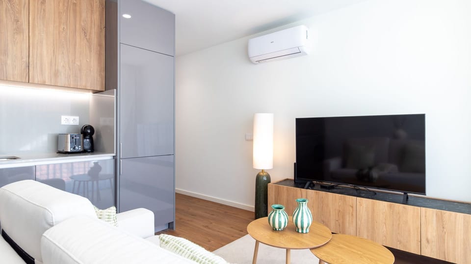 Unwind after a day of exploring in the comfortable living area, featuring a large flat-screen TV for entertainment and stylish decor. This inviting space seamlessly connects to the kitchen, making it ideal for socializing and relaxing.