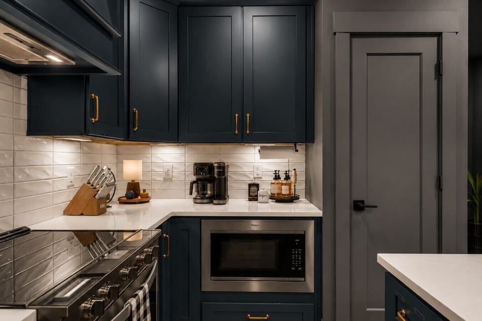 Gourmet kitchen setup featuring deep navy shaker cabinets and elegant gold hardware.