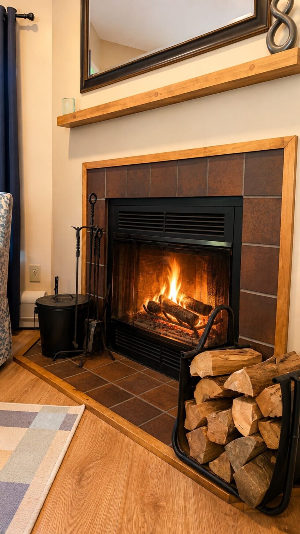 10 - Fireplace Detail - Close-up of the tiled wood-burning fireplace with tools and firewood