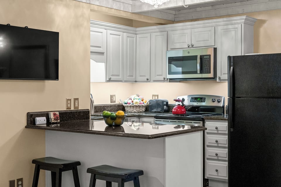 Bright full kitchen with breakfast bar, TV, and modern appliances