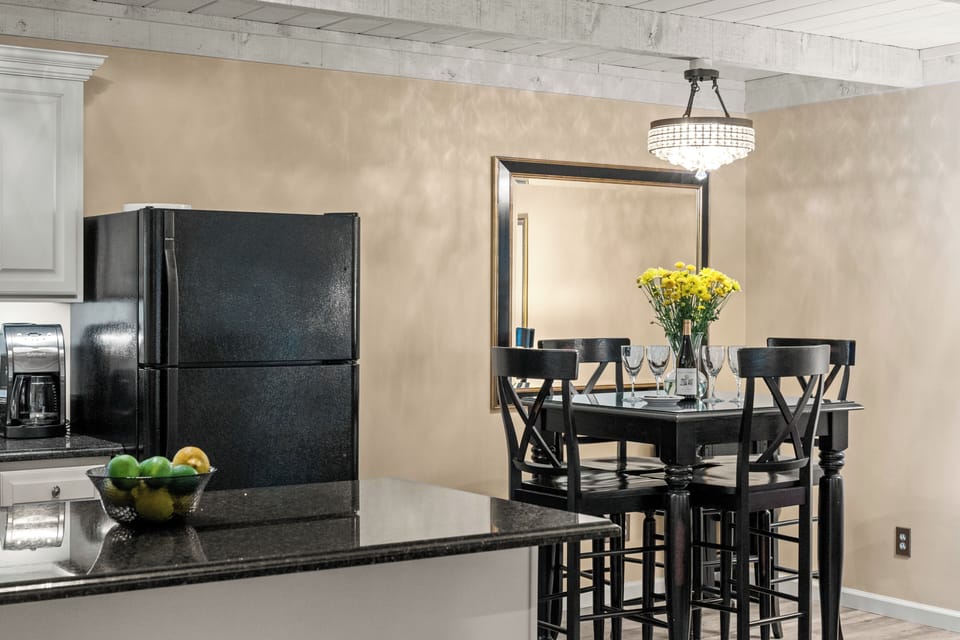 Elegant dining nook with chandelier, mirror, and open kitchen access