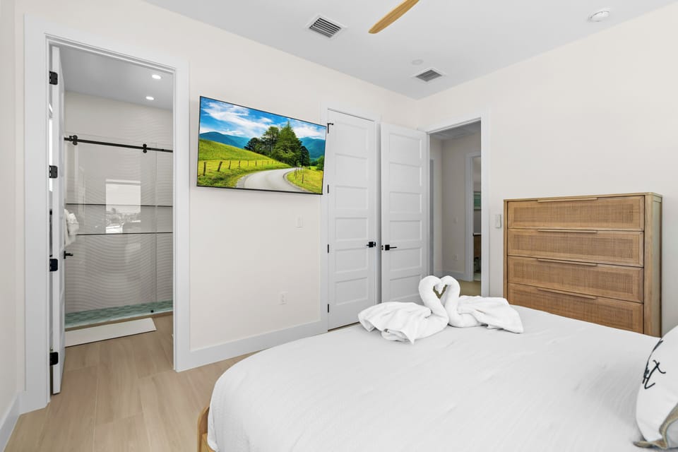 Bedroom view toward the wall-mounted television and private bathroom entrance.