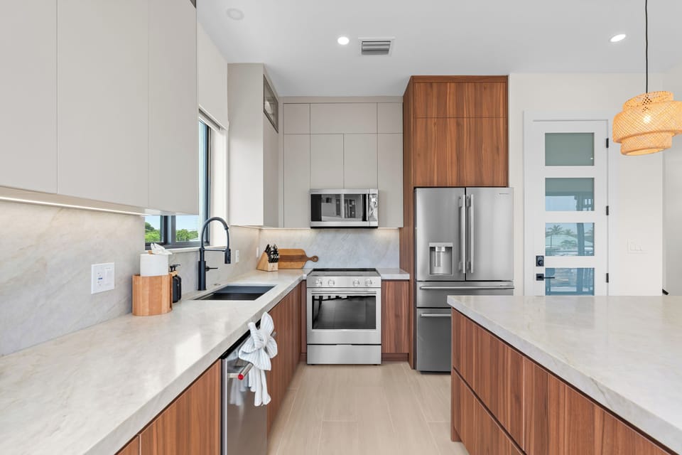 Well-equipped kitchen workspace with stone counters, stainless appliances, and warm wood cabinetry.