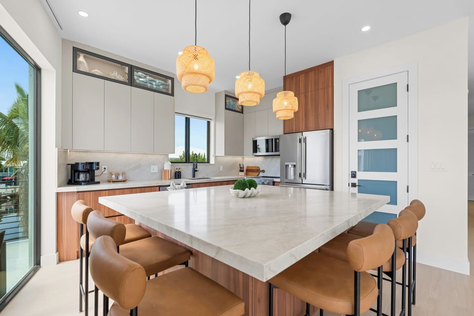 Modern kitchen with a large stone island, wood cabinetry, pendant lights, and bar seating.