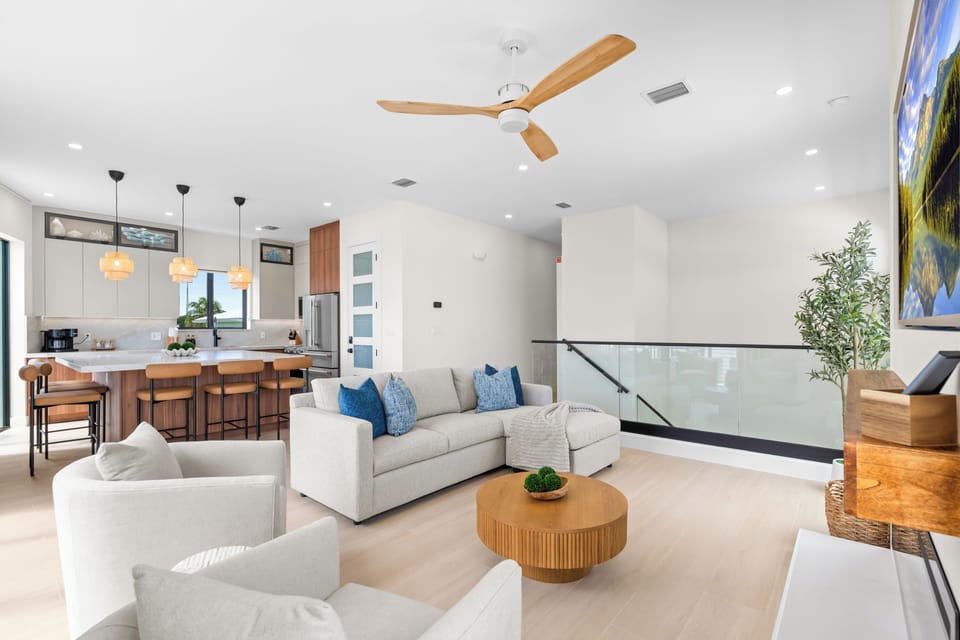 Open-plan living area with lounge seating, kitchen island, and glass doors leading outside.
