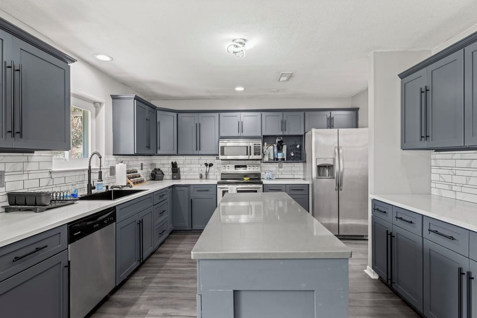A chef's dream — spacious island seating, sleek gray cabinetry, and stainless steel appliances throughout.