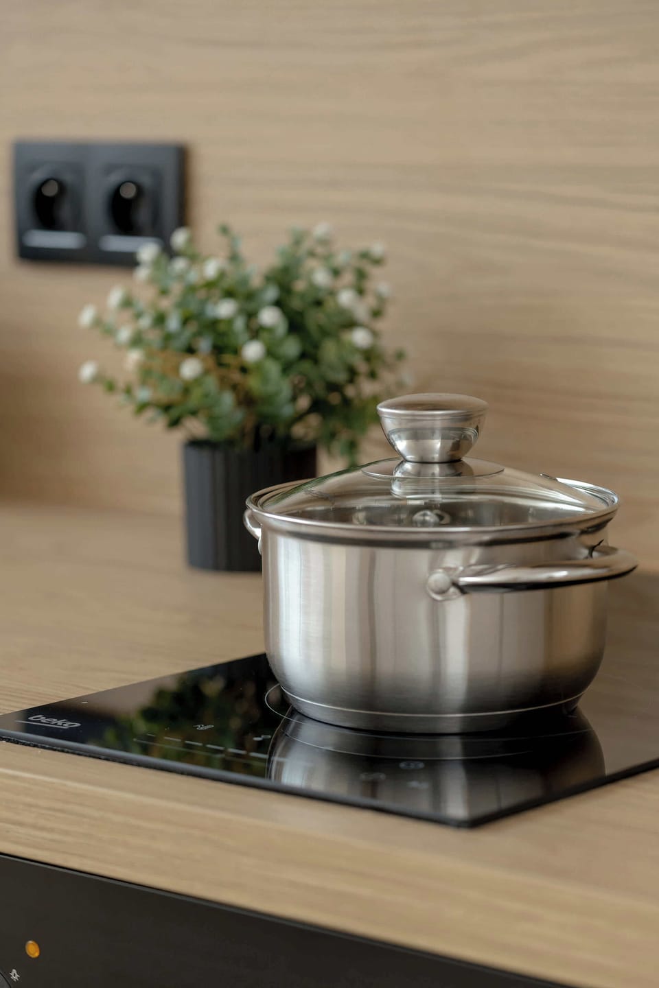 A small decorative arrangement with a stainless-steel pot and kitchen accessories placed on a countertop.