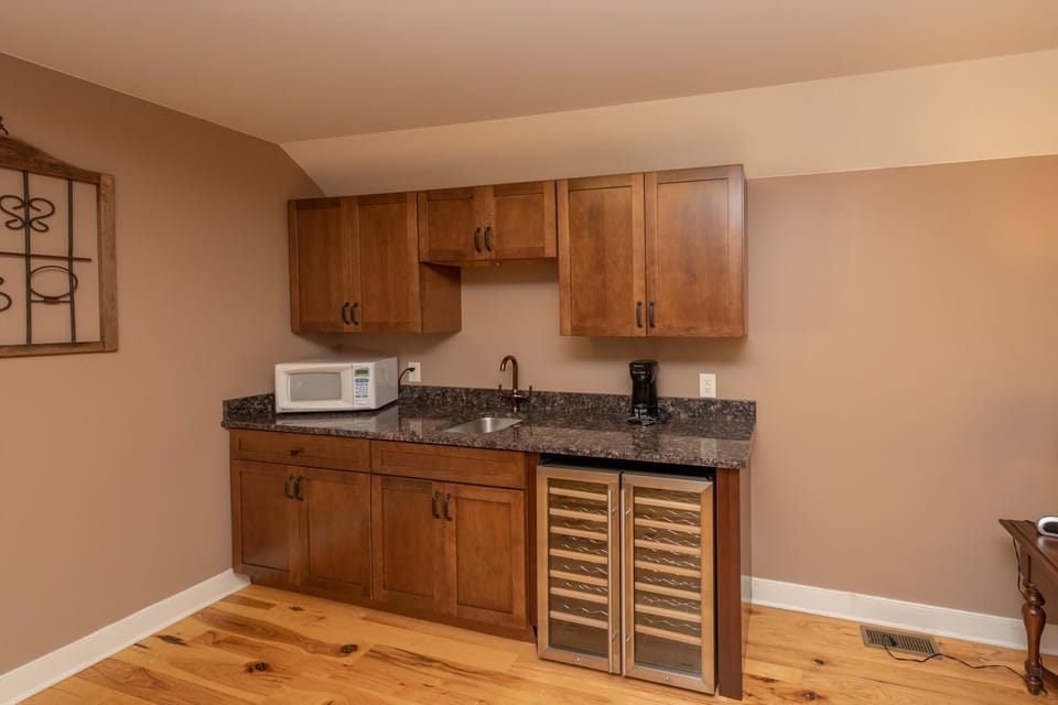 Pool house lounge wet bar with microwave and beverage fridge.