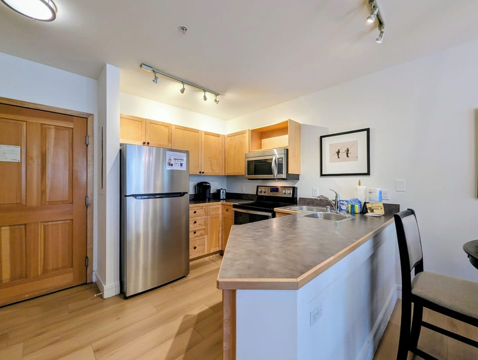 Step into your modern kitchen with sleek stainless steel appliances, warm wood cabinetry, and plenty of counter space for preparing meals during your stay.