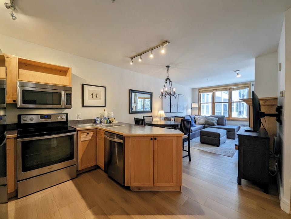 Step into your bright, open-plan retreat where the warmth of natural wood meets modern comfort. The fully-equipped kitchen flows seamlessly into a cozy living space with plush seating, perfect for unwinding after a day of adventure.