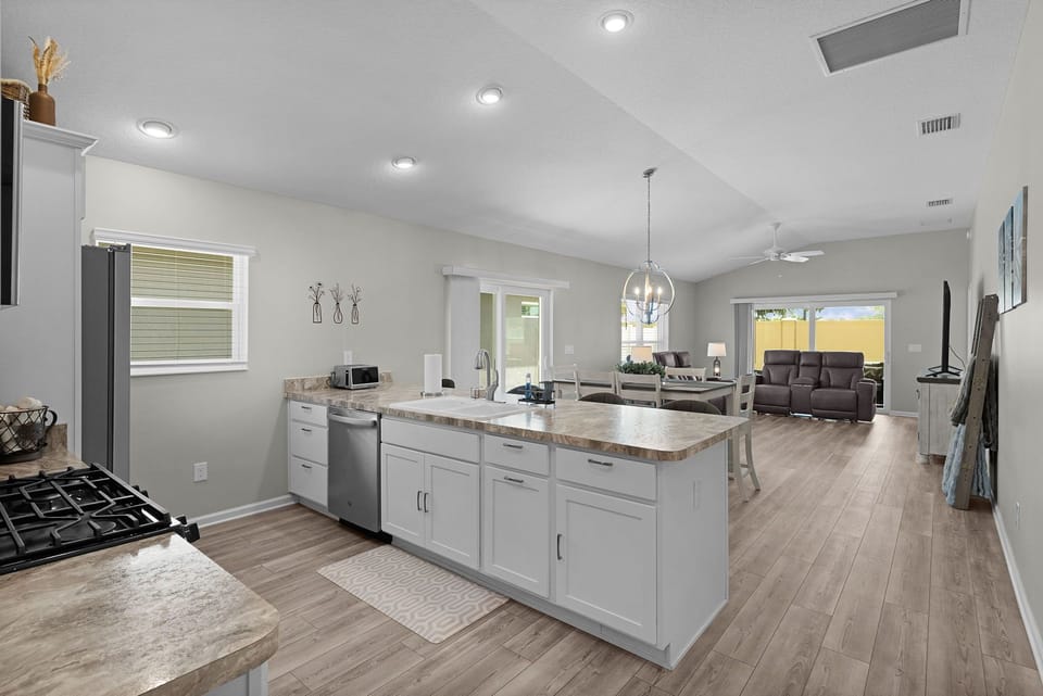 Step into your open-concept retreat where the kitchen flows seamlessly into a bright living space. Natural light fills the room while vaulted ceilings and modern finishes create an airy, inviting atmosphere perfect for relaxing and entertaining.