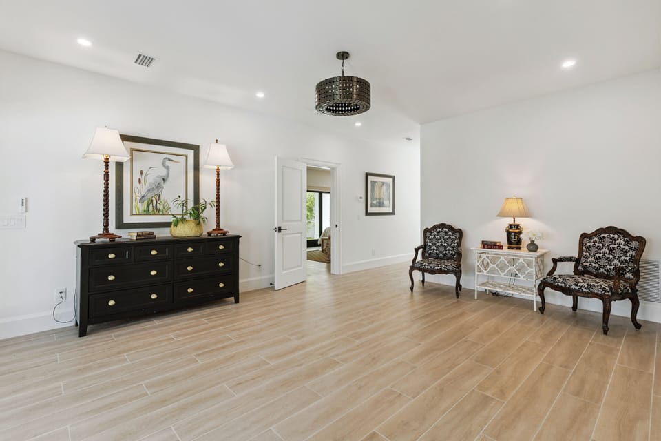 Step into your elegant sitting room, where soft lighting and refined furnishings create a sophisticated retreat. The warm wood-look floors and classic décor invite you to unwind in comfort and style.