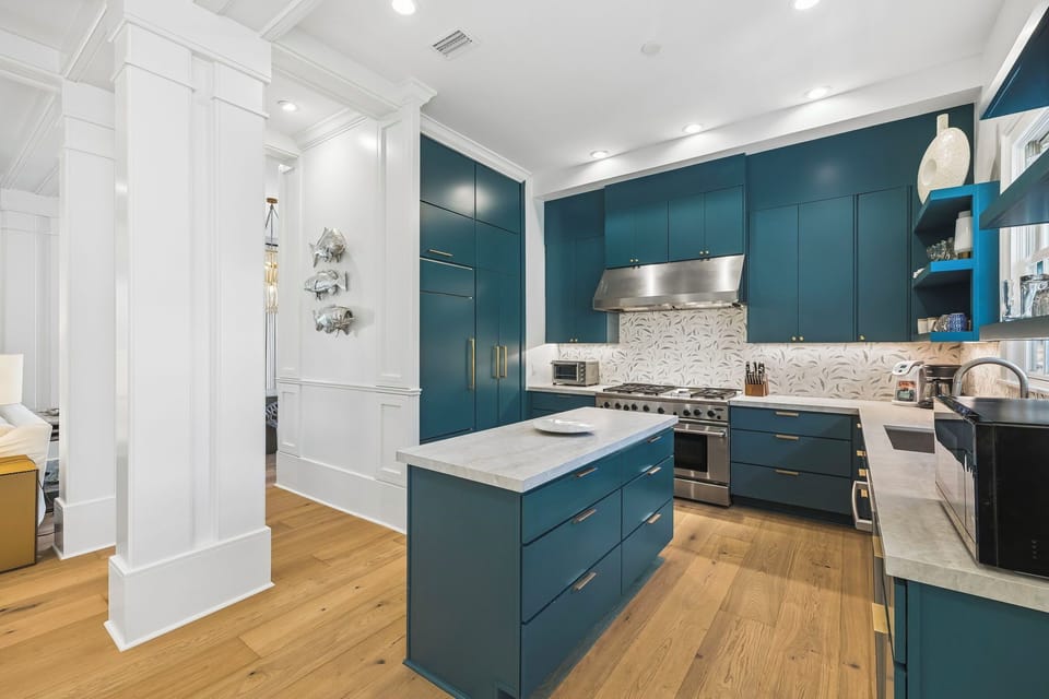 Your gourmet kitchen awaits with deep teal cabinetry, marble countertops, and top-tier appliances—perfect for crafting memorable meals during your stay.