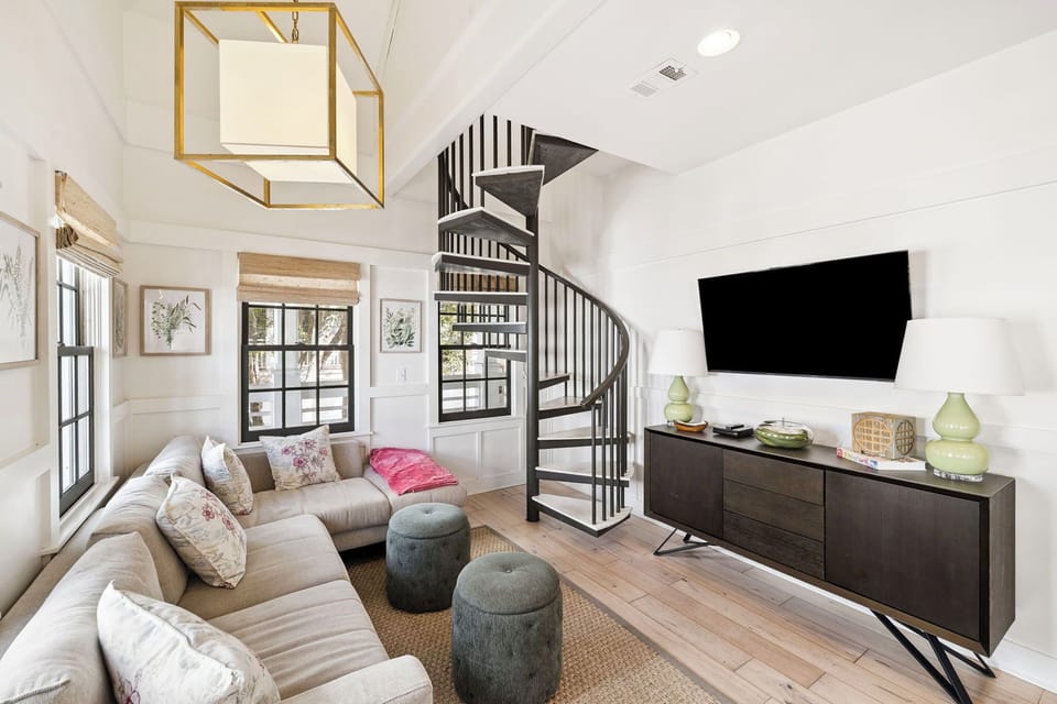 Curl up in this stylish living space featuring a plush sectional sofa and modern spiral staircase.