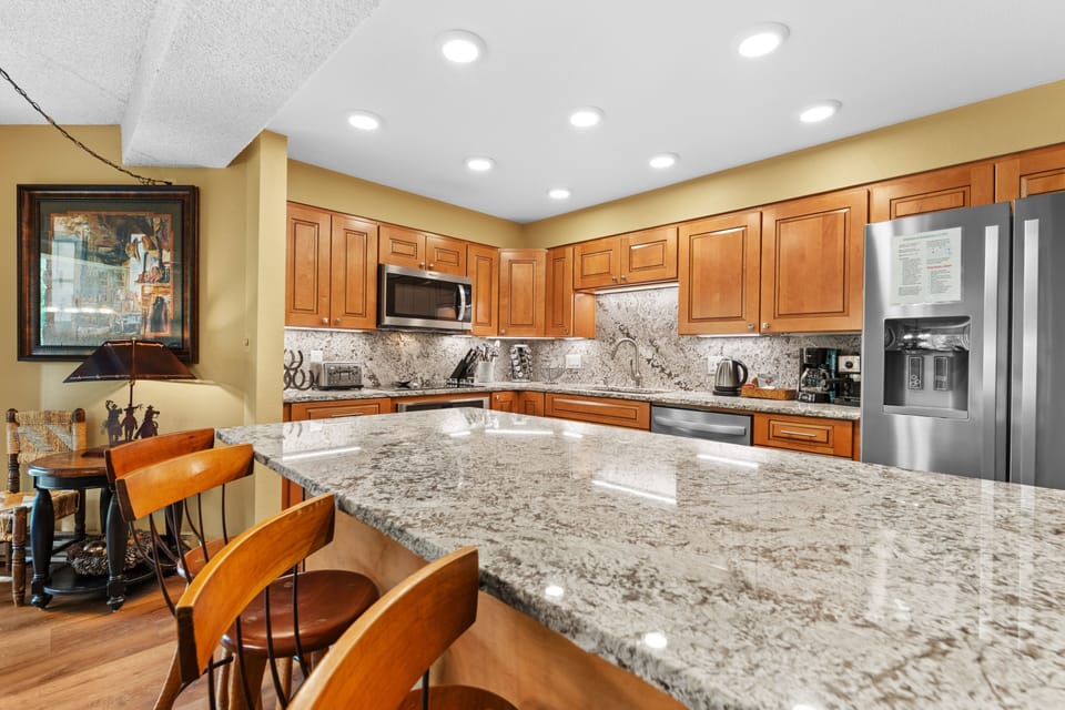 Your gourmet kitchen gleams with granite countertops, stainless steel appliances, and rich wood cabinetry. Gather at the island bar for coffee or meal prep—this space invites you to cook, connect, and savor every moment.