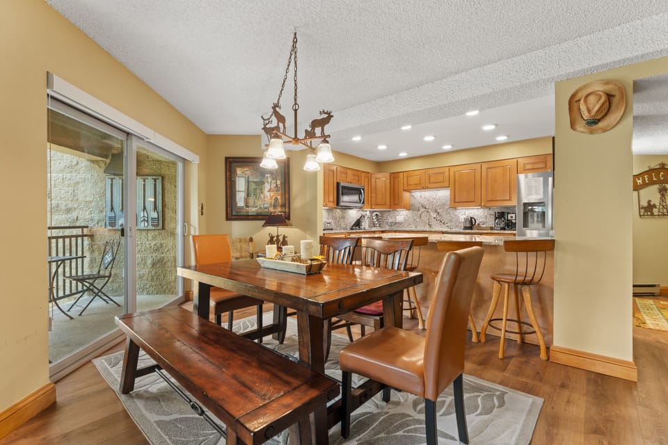 Gather around the inviting dining table with your group, where the open kitchen and cozy western touches create the perfect setting for memorable meals together.