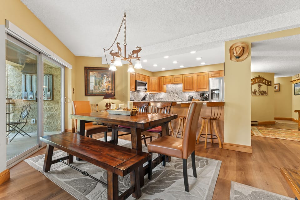 Gather around this handsome farmhouse table for meals and memories. The open layout flows seamlessly from dining to kitchen, with rustic charm and access to your private patio just steps away.