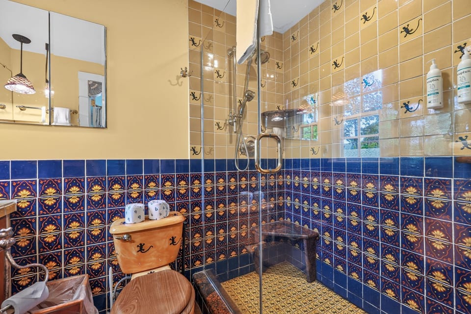Bathroom featuring a walk-in glass shower and decorative blue and tan tiling.