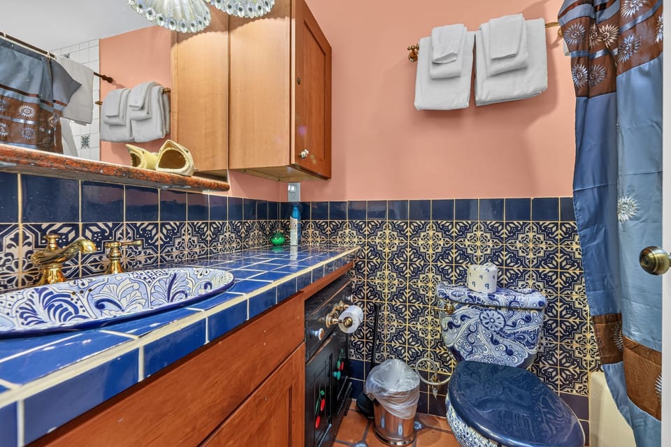 Vibrant bathroom featuring decorative blue tilework, an ornate sink, and matching toilet.