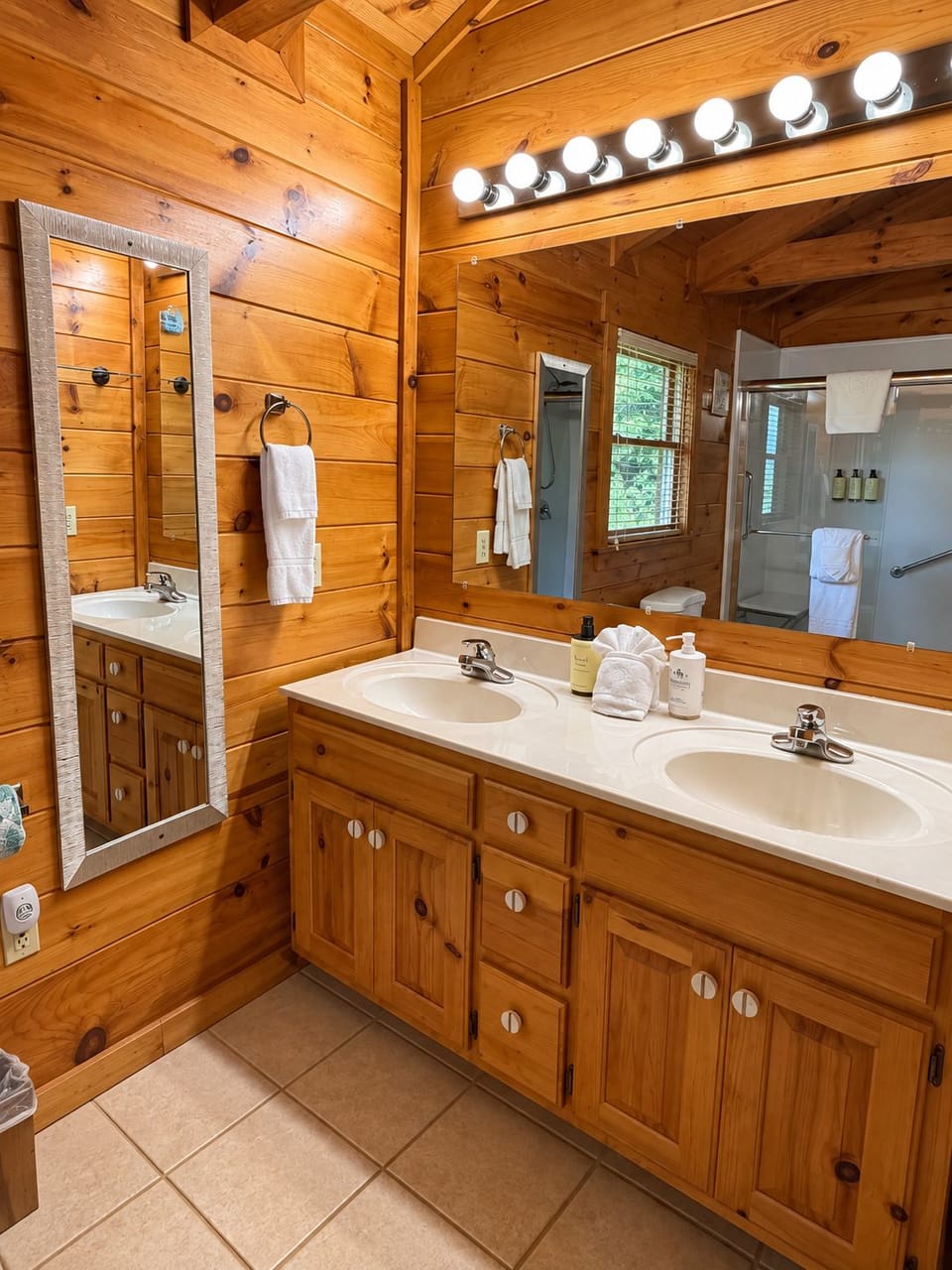 Rustic double-vanity bathroom with bright lighting and spacious shower