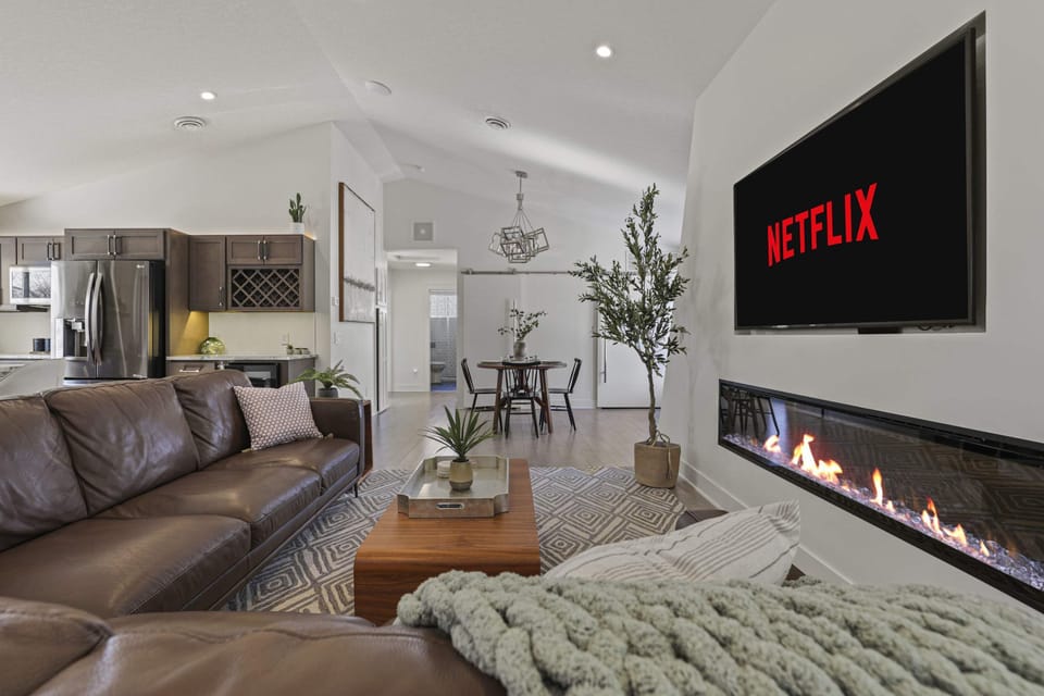 Open concept living area with high end leather couch, gas fire place, and 65" smart TV.