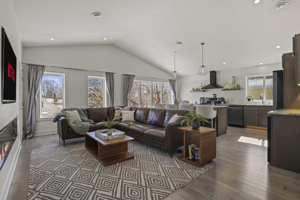 Open concept living area with high end leather couch, gas fire place, and 65" smart TV.