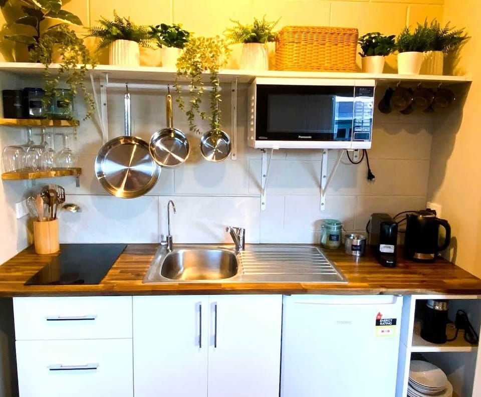 Studio Kitchenette downstairs with hob, microwave, fridge, water filter tap, coffee machine, premium tea and coffee, kitchen utensils.