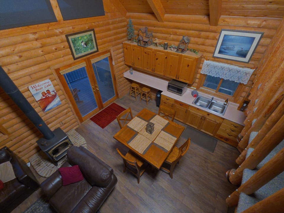 Cozy log cabin great room with wood stove, dining area, and deck access