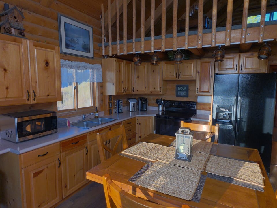Rustic cabin kitchen with loft views, dining table, and warm wood charm