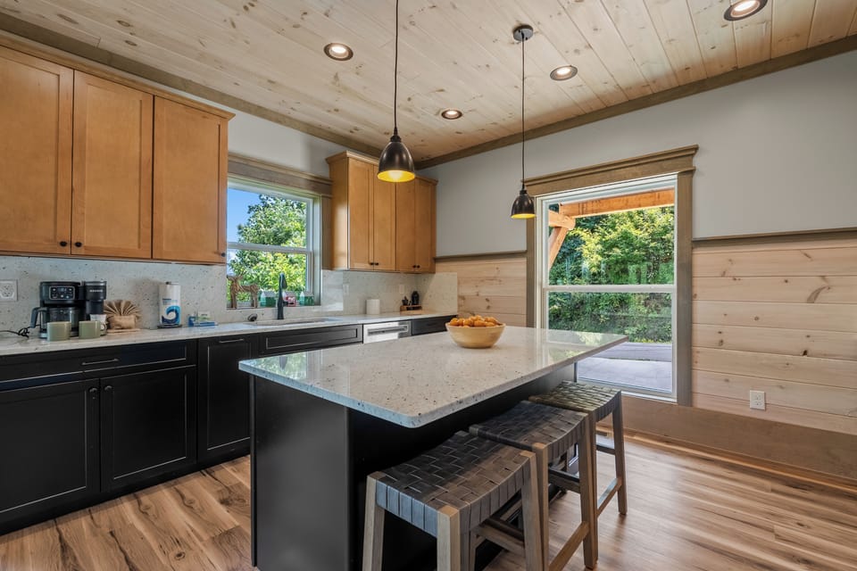Bright mountain lodge kitchen featuring a large island with bar seating, generous counter space, and natural wood finishes.