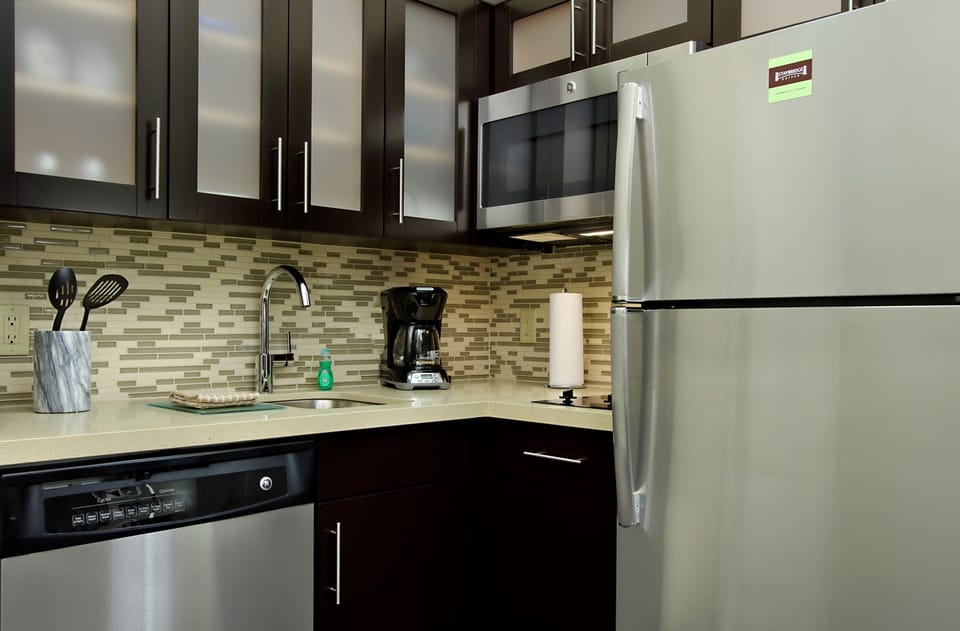 Modern kitchen with stainless appliances, tile accents, stovetop, microwave, and dishwasher — meals made easy
