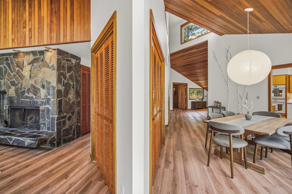 Gather around the handcrafted dining table under soaring vaulted ceilings, where warm wood tones and modern comfort invite your group to share meals and make memories together in this thoughtfully designed space.