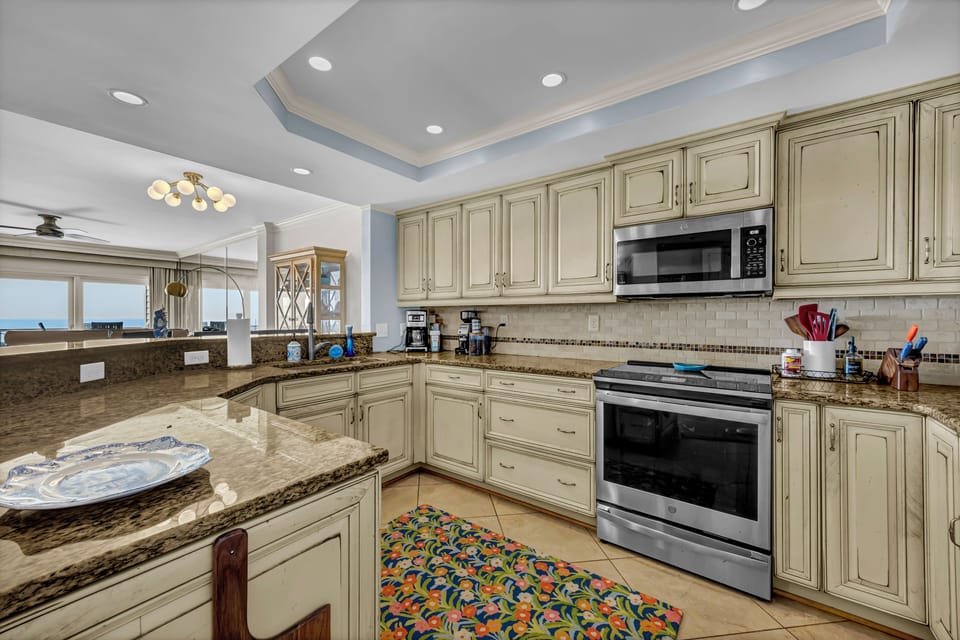 Cook your favorite meals in this spacious, fully-equipped kitchen with granite countertops, modern appliances, and a glimpse of the ocean beyond—perfect for your coastal retreat.