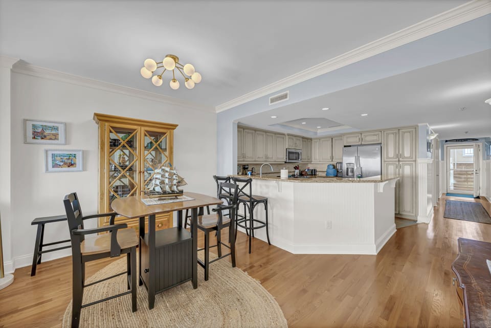 Gather around the kitchen island for morning coffee or evening drinks in this bright, open space. Coastal charm meets modern comfort with warm wood floors, elegant cabinetry, and thoughtful nautical touches that make your vacation feel like home.