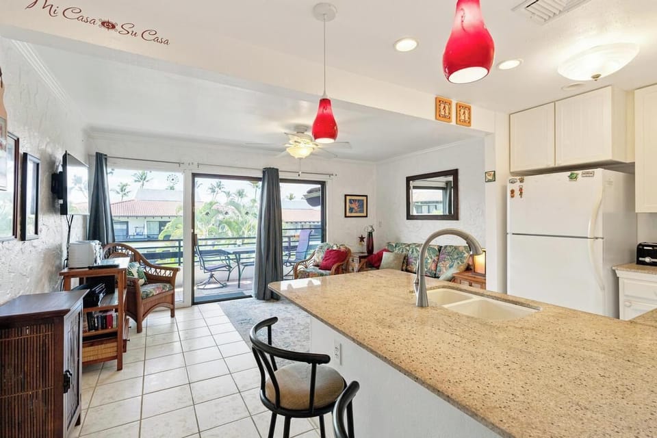 Your bright open-plan kitchen and living area feels welcoming from the moment you arrive, with vibrant red pendant lights overhead and a well-equipped space to prepare meals and relax.