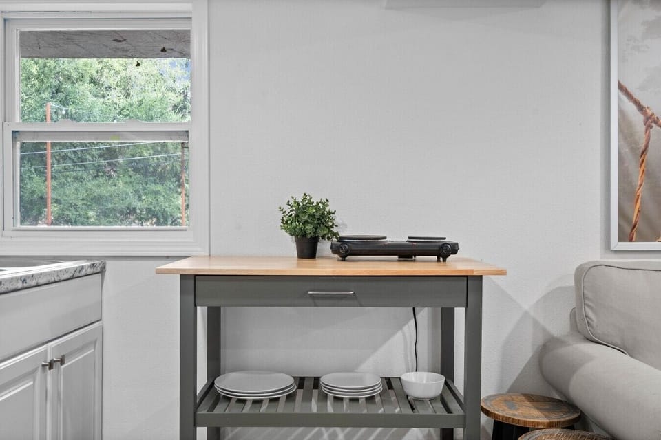 The butcher-block cart holds a portable cooktop and dishware, ready for a simple home-cooked meal.