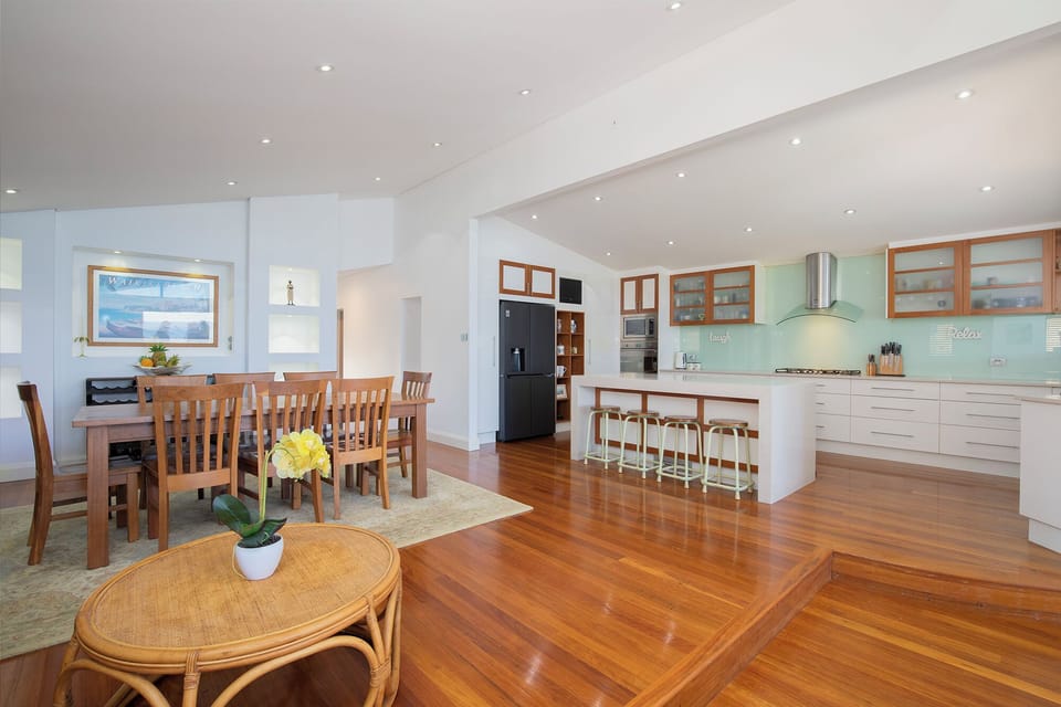 The open-plan upper level connects generous living, dining and kitchen spaces, creating a welcoming hub for sharing meals, conversation and coastal views.
