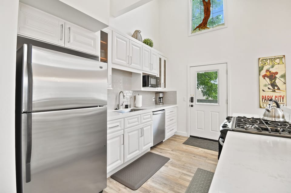 Your fully equipped kitchen features modern stainless steel appliances, ample white cabinetry, and bright natural light—perfect for preparing your favorite meals during your mountain getaway.