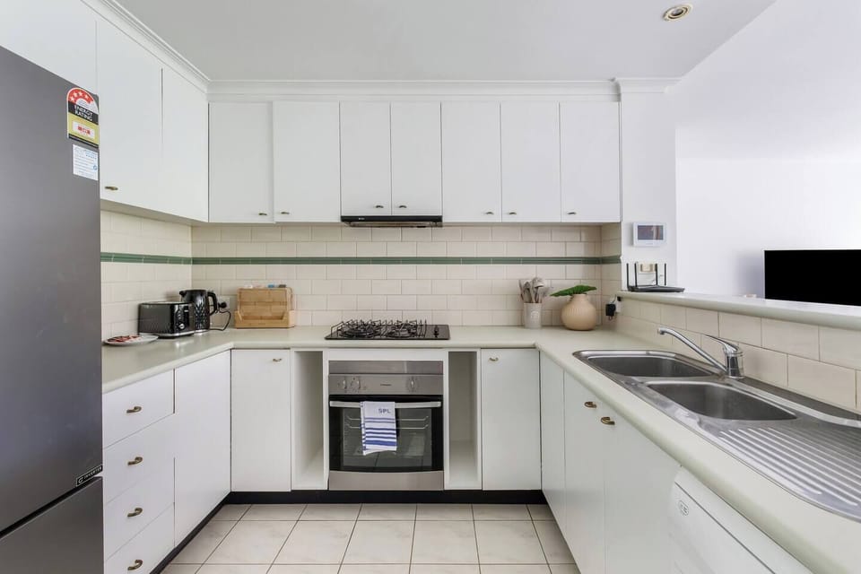 Equipped with a gas cooktop, oven, microwave, dishwasher, and full-sized fridge, the kitchen is designed for effortless cooking and home-style dining.