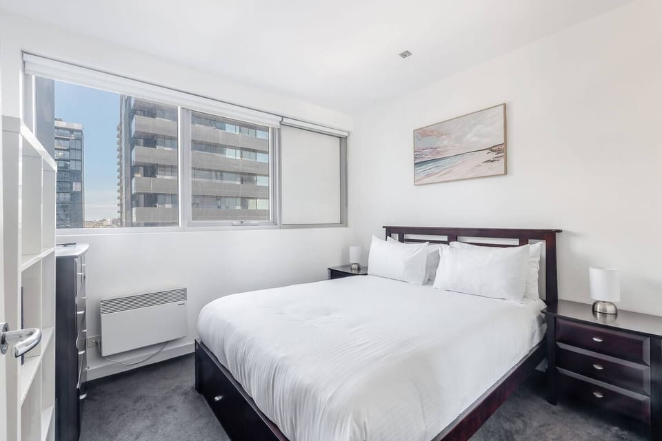 Rest well in the bedroom, where a queen bed dressed in crisp white linen and a bright city outlook set the tone for easy mornings.