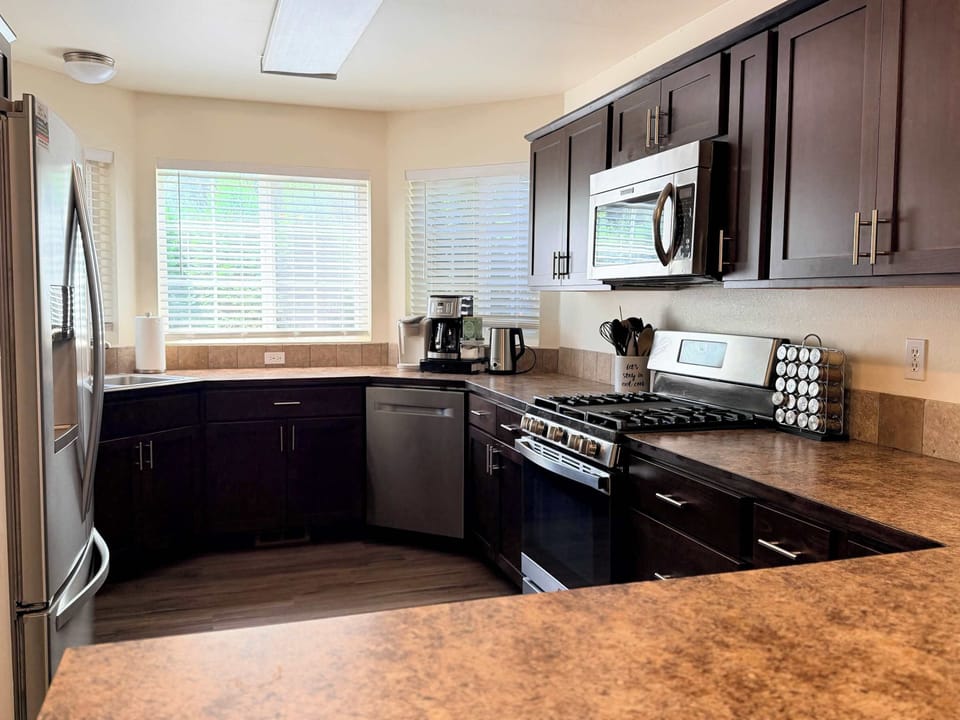 Well-equipped kitchen with stainless steel appliances, gas range, dishwasher, microwave, coffee station, toaster, and generous counter space.