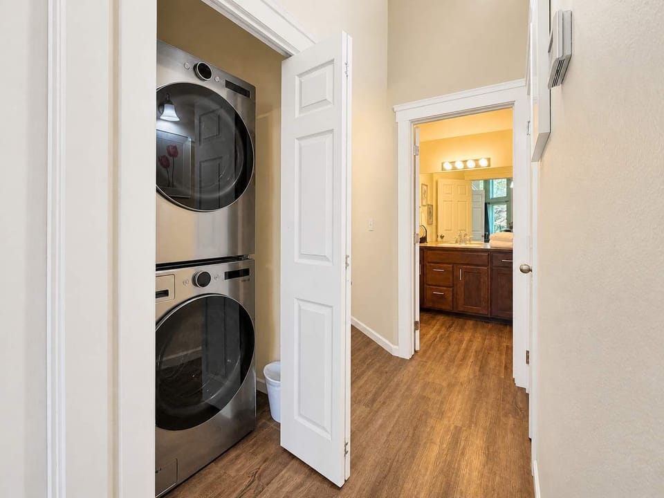 Hallway with in-unit stacked washer/dryer closet steps from the bathroom — pack light knowing laundry is handled